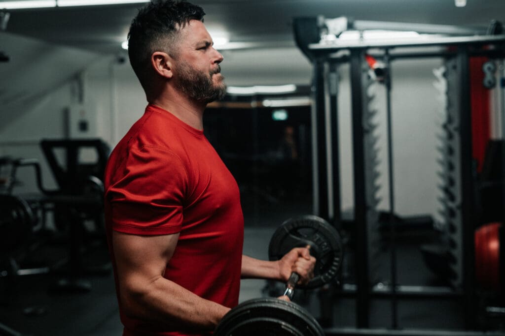 Side view of a man lifting an EZ curl bar in a gym